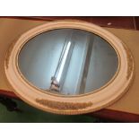 A white and gilt framed oval mirror
