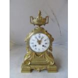 A 19th Century gilt mantel clock with urn finial, white painted dial and scroll front on square