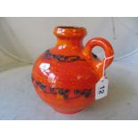 A West German pottery single handled jug with orange and red mottle ground and black lava style