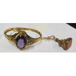 A gold coloured bangle bracelet purple stone and a seal