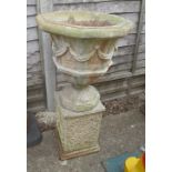 A pair of reconstituted stone garden urns and stands