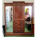 A Victorian mahogany triple wardrobe with two side mirrored doors, central cupboard and four