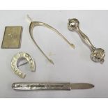 A silver rattle (slightly dented), wishbone tongs, horseshoe brooch, retractable knife and small