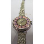 A silver watch with pink enamel chapter ring on metal strap
