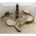 A silver sugar caster, silver backed brushes, mirror, pair of squat candlesticks and a napkin ring