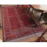 A madder ground Persian rug with panels of hooked black design and diamond pattern borders