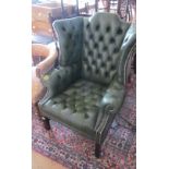 A green button upholstered wing armchair (arms patched)