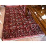 A madder ground Bokhara rug with four rows of seven guls with starburst and geometric borders