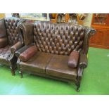 A brown buttoned upholstered wing style settee
