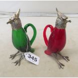 A pair of glass decanters one red, one green in the form of parrots with white metal heads and feet