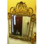 A decorative gilt mirror with shell motif cresting