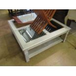A large limed wood coffee table with glass inset top