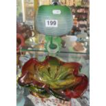 A red and green glass frilled edge dish and a green spherical glass bowl on leaf stem