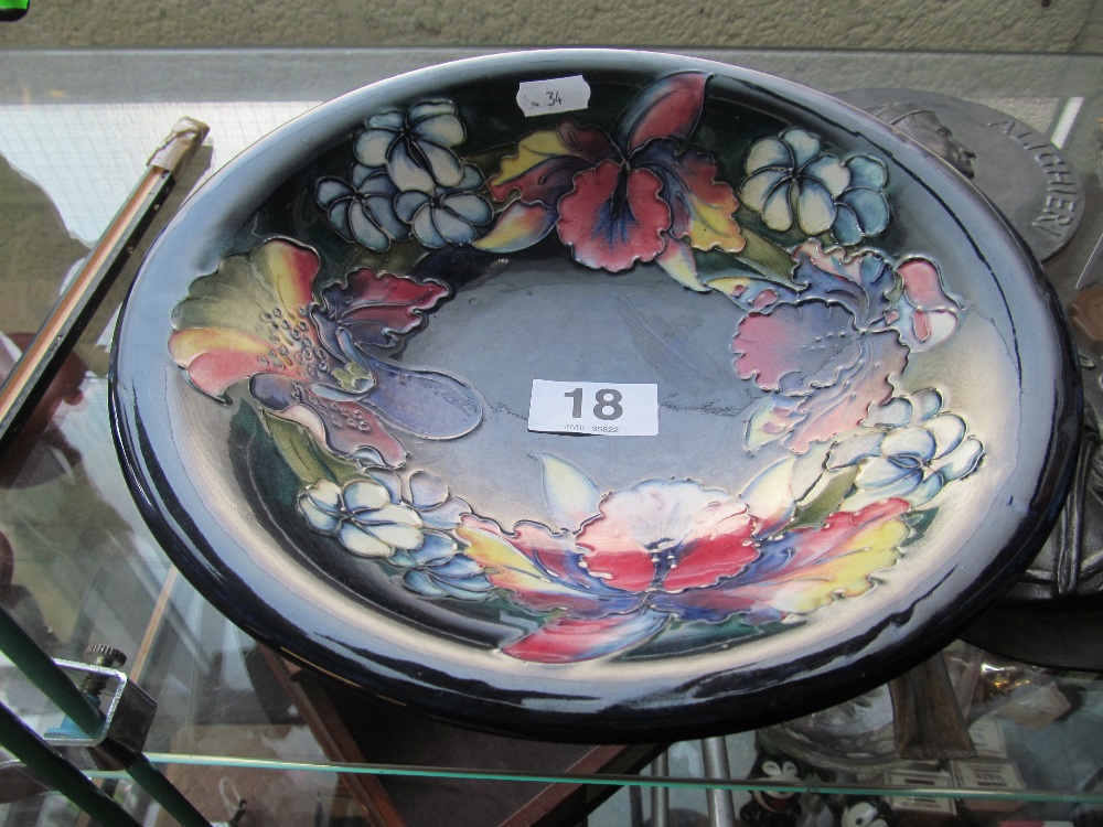 A Moorcroft dark blue glazed bowl decorated pink and blue flowers