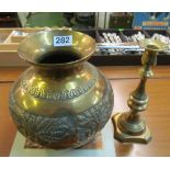 A brass vase embossed figures and horses and a brass candlestick