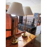 A pair of gilt and silver coloured tall lamps with cream shades