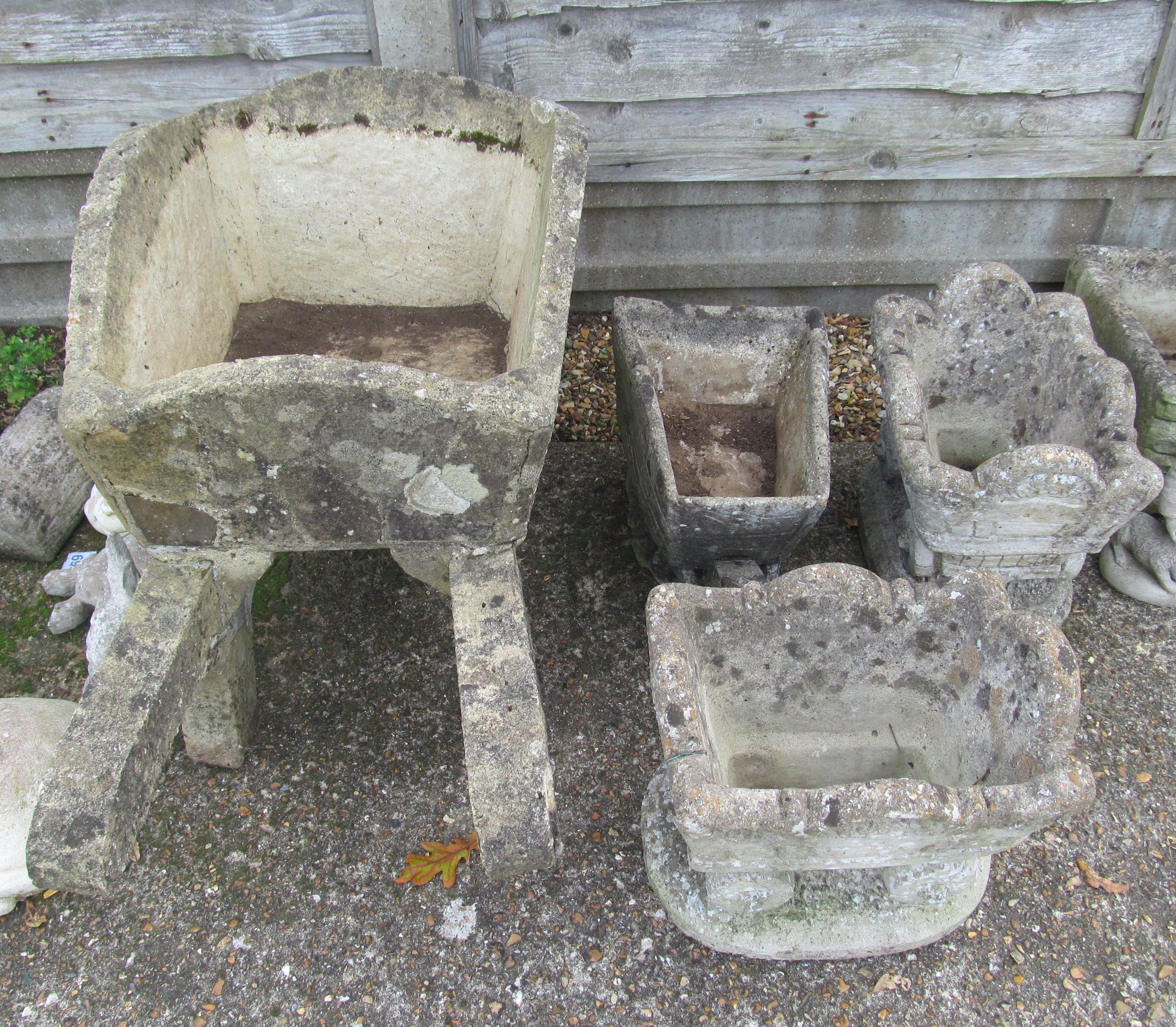 A concrete wheelbarrow planter, smaller one and two carriages