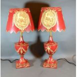 A Pair of Toleware Table Lamps decorated with bows and swags upon a red ground, 54 cms tall