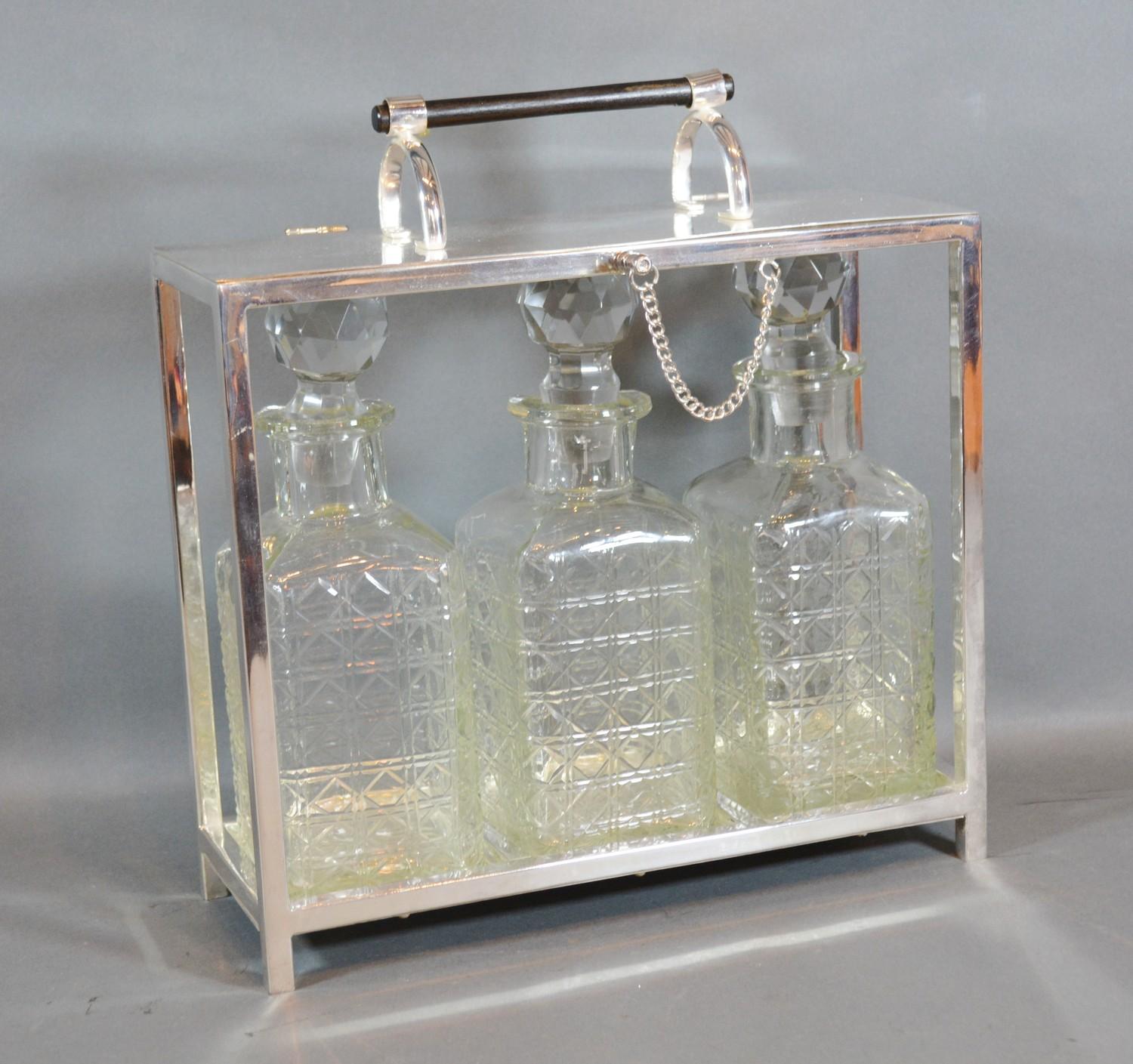 A Silver Plated Tantalus, the hinged top above three cut glass decanter with stoppers 28cm by 10cm