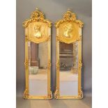 A Pair of French Style Gilded Dressing Mirrors each with a scroll carved cresting above a panel