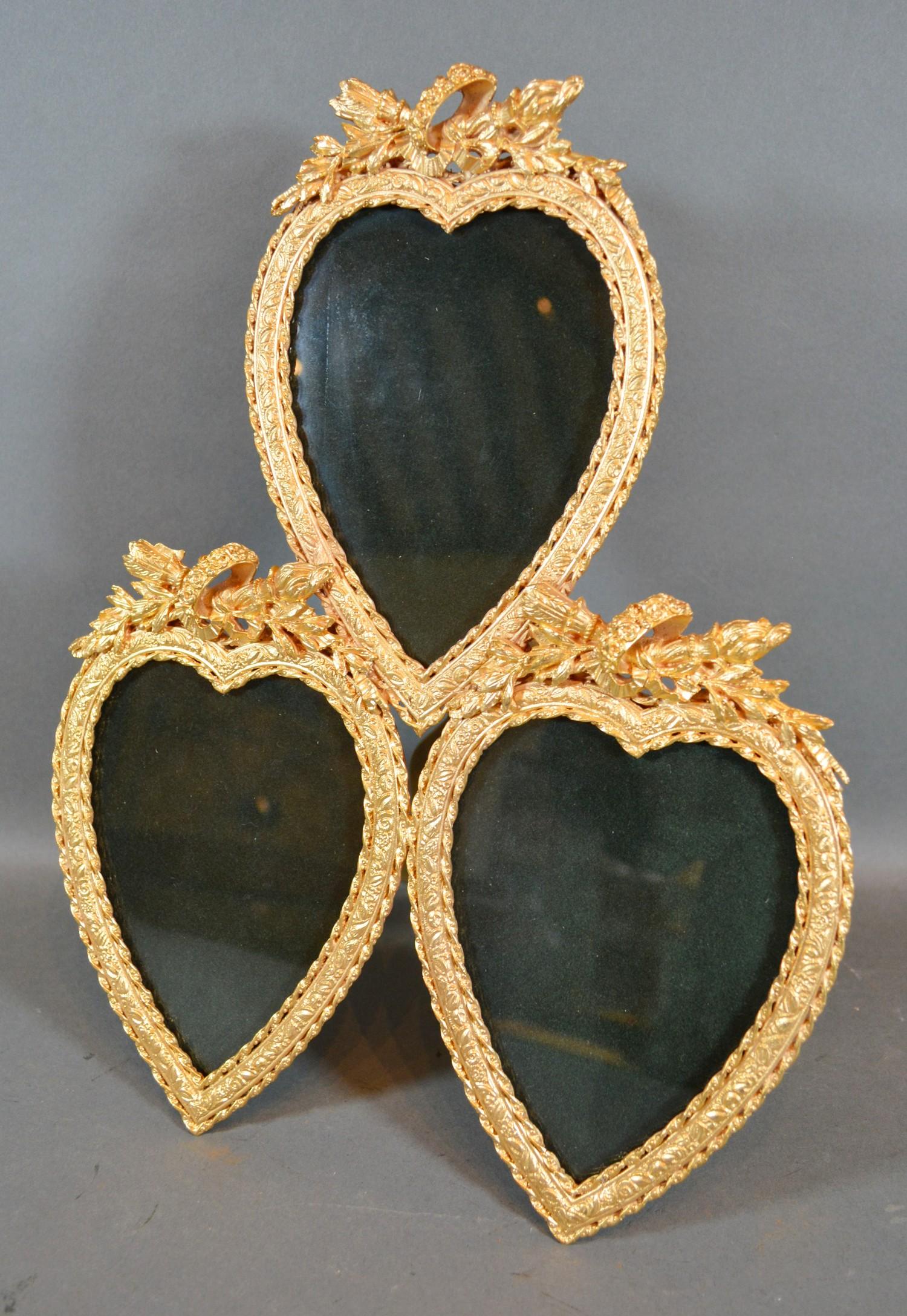 A Gilt Metal Triple Photograph Frame of heart form with torch and quiver cresting 25cm by 31cm tall