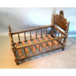 A Late 19th Century French Cradle with a shaped scroll headboard and turned spindles, 92 cms long
