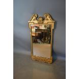 A Gilt Framed Wall Mirror, the swan neck pediment above the rectangular plate and with shaped