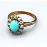 A Yellow Metal Turquoise and Diamond Set Cluster Ring with a central oval cabochon turquoise