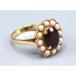 A 9ct. Gold Garnet and Pearl Cluster Ring with a central oval garnet surrounded by pearls within a