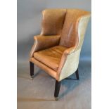 A Leather Uphostered Wingback Armchair with square tapering legs, brass caps and castors