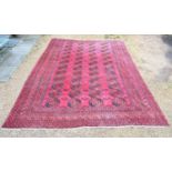 An Afghan Woollen Carpet with four rows of guls upon a red ground within multiple borders, 540 x 347