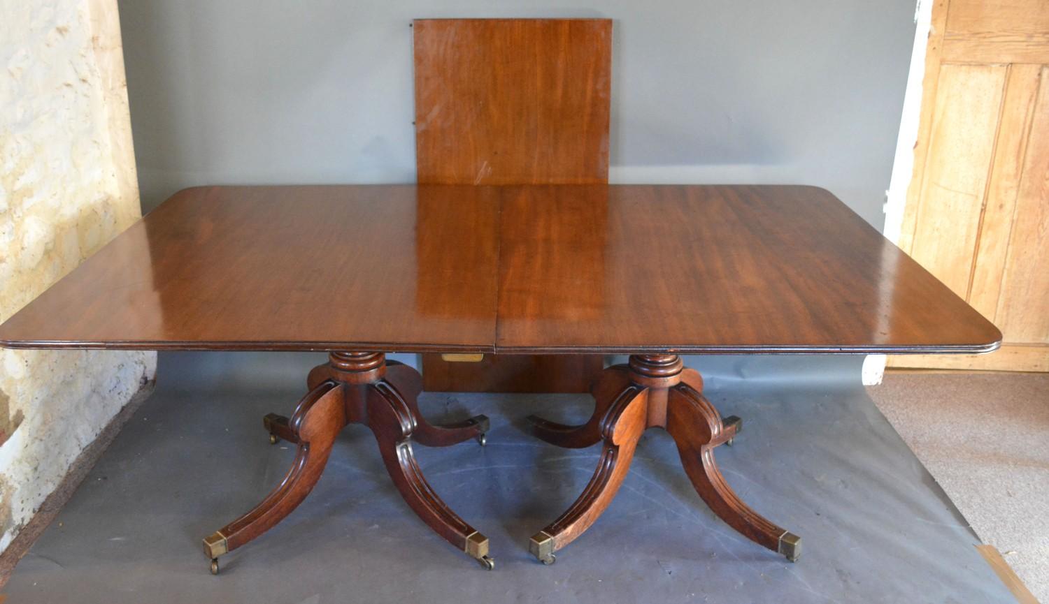 A Regency Mahogany Dining Table, the reeded top above twin end turned supports with reeded