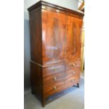 A Regency Mahogany Linen Press, the moulded cornice above two oval panel doors enclosing sliding