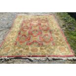 An Agra Woollen Rug with an all over design upon a red and cream ground within multiple borders, 266
