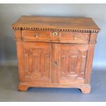 A George III Oak Side Cabinet with a frieze drawer above two geometrically moulded doors enclosing