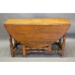 A George III Oak Oval Gateleg Dining Table with a frieze drawer raised upon turned legs with