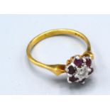 An 18ct. Gold Ruby and Diamond Cluster Ring with a central diamond surrounded by rubies, claw set,
