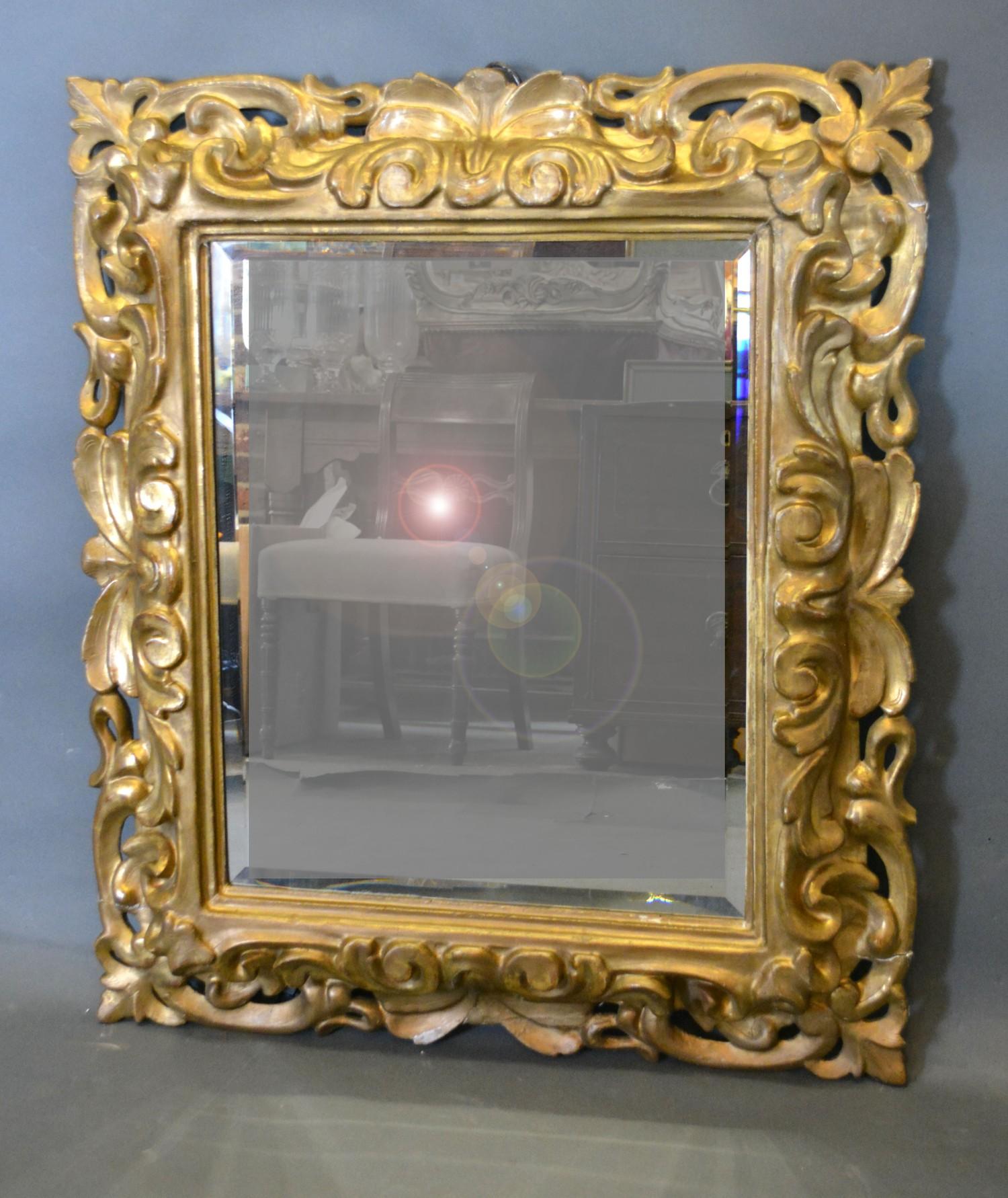 A 19th Century Giltwood Cushion Mirror with scroll carved and pierced frame, 90 x 77 cms