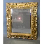 A 19th Century Giltwood Cushion Mirror with scroll carved and pierced frame, 90 x 77 cms