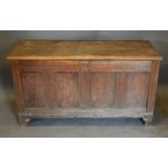 An 18th Century Oak Coffer, the plank top above a four panel front flanked by stiles, 138 cms wide x