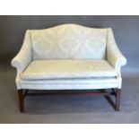 A Small Upholstered Hump Back Settee with scroll arms raised upon square legs with stretchers,