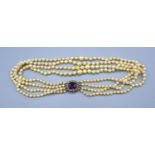 A Cultured Graduated Pearl Four Strand Choker, the yellow metal clasps set with an amethyst