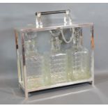 A Silver Plated Tantalus, the hinged top above three cut glass decanter with stoppers 28cm by 10cm