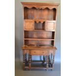 An Oak Dresser, the moulded cornice above a boarded shelf back with two cupboards, the lower section