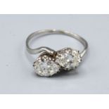 A white gold diamond set crossover ring, set with two diamonds within a pierced setting,