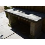A weathered cast concrete garden bench together with a bird bath