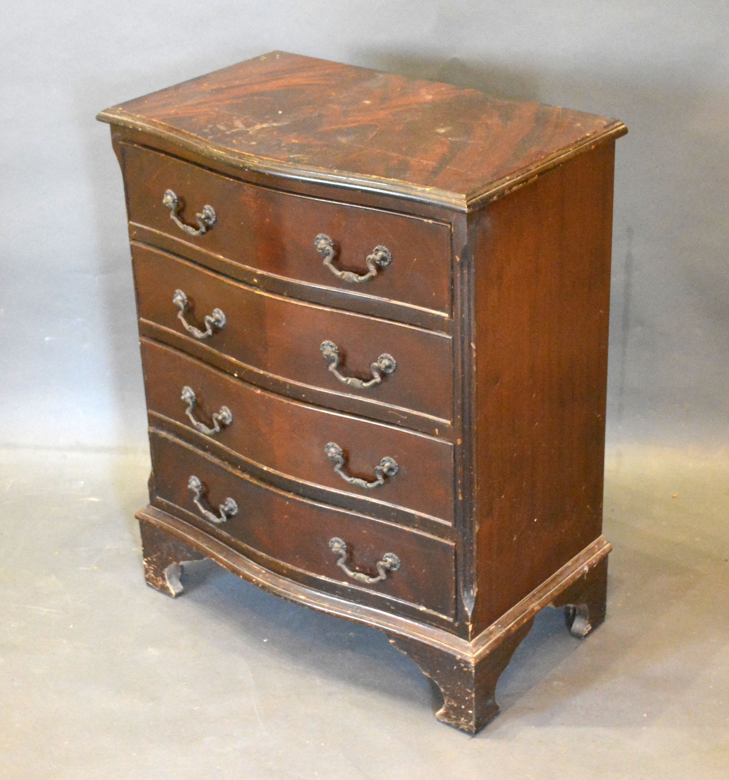 A 20th Century Mahogany Serpentine Chest of four long drawers with brass handles raised upon bracket