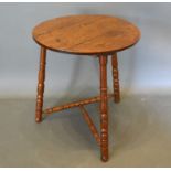 An oak cricket table, the circular top above three turned supports with stretchers, 48cms