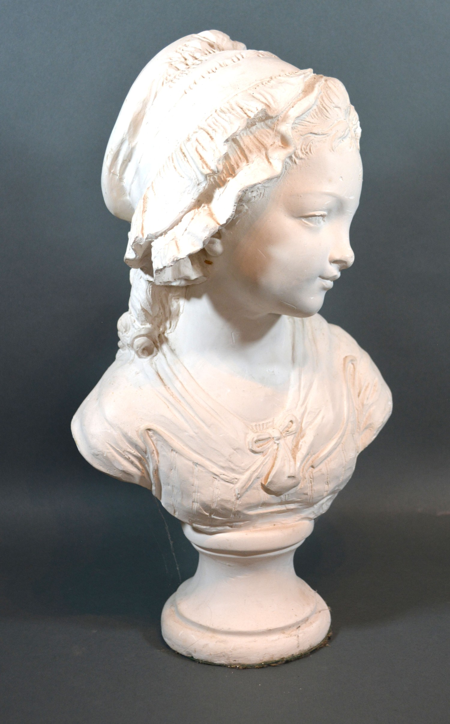 A plaster bust in the form of a girl wearing a bonnet 45cm tall