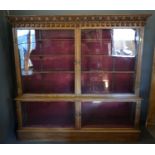 An early 20th century oak large display cabinet, the moulded cornice above two glazed doors, the